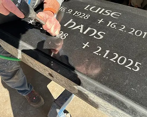 Schwarzer Grabstein Auf einem schwarzer Grabstein wird ein Sterbedatum eingemeiselt