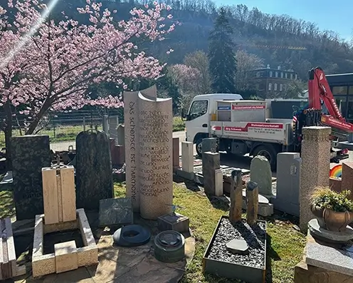 In der Hofeinfahrt von Steinmetz Schwenk steht der eigene LKW und viele Steinarbeiten und einem Kirschbaum
