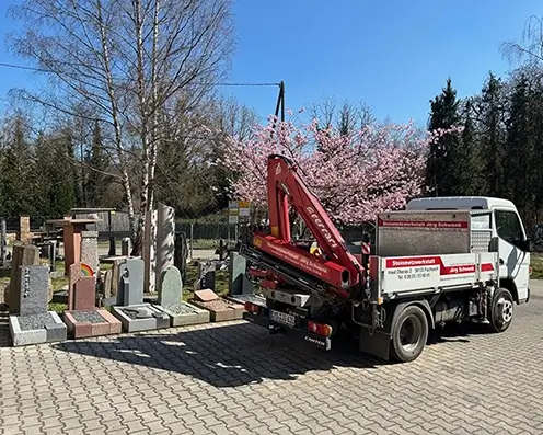 In der Hofeinfahrt von Steinmetz Schwenk steht der eigene LKW und viele Steinarbeiten und einem Kirschbaum