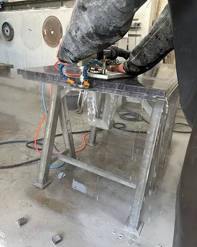 Ein Mitarbeiter in der Werkstatt betätigt die Steinschleifermaschine